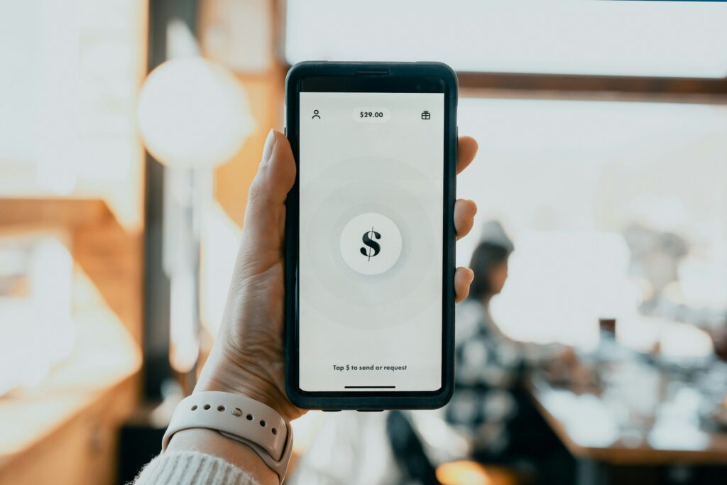 Hand holding a phone with a Shopify symbol on it